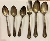 Six silver-plated utensils on white background