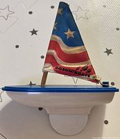 Full view of toy sailboat, showing hull, deck, mast and sail