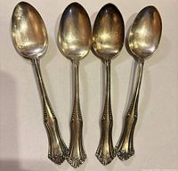 Front view of four ornate sterling spoons