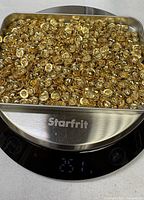 Tray on digital scale reading 251 g filled with gold-tone metal findings