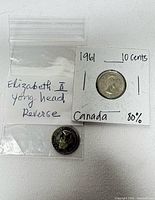 Two coins: one in 2×2 holder marked 1961 10 cents Canada 80%, one loose in bag