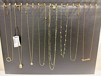 All eight gold-tone necklaces hung on display board
