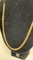Full view of gold curb chain necklace on black bust