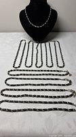 Group view of all ten beaded necklaces laid flat showing length and uniform style