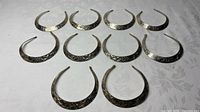 All eleven engraved silver-tone collar necklaces arranged in rows