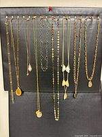 Group shot of 13 gold-tone necklaces hanging