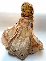 Full view of doll in peach dress and bonnet