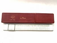 Slide rule beside closed red hard case showing branding