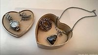 Overview showing watch, two brooches and Buddha pendant necklace in heart boxes