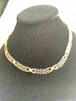 Full view of necklace on bust showing woven silver links and gold accents