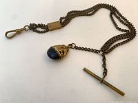 Full view of Albert chain showing clasp, slide, T-bar and red glass fob