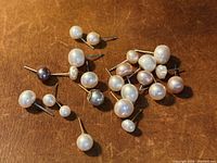 Assorted single pearl studs spread on surface
