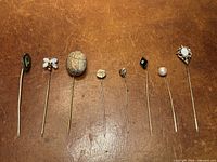 All eight stick pins laid out on leather surface