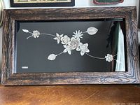 Full view of framed silver floral artwork on black background