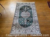 Full view of silk Persian rug on wood floor