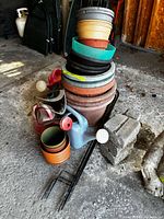 Stacked plastic pots, watering cans, shepherd hook parts visible