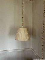 Pendant light turned off showing pleated shade and chain