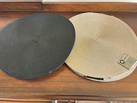 Black and gray placemats stacked on wooden surface