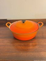 Dutch oven with lid, orange exterior, side handles