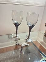 Two wine glasses and matching corkscrew on glass surface