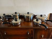 Group shot of six lidded Saladmaster pots and pans on dresser
