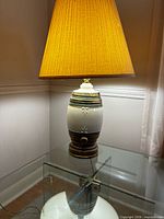 Full view of ceramic lamp with shade on glass table