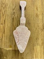 Top view of pink ceramic cake server showing embossed floral design