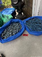 Two blue trays holding concrete screws and metric bolts