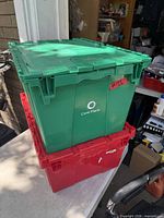 Green and red plastic totes stacked showing folding lids and Core-Mark logo on green tote