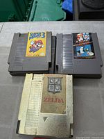 Front view of three NES cartridges: Super Mario Bros. 3, Duck Hunt, The Legend of Zelda