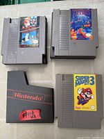 Front view of three NES cartridges and one empty dust sleeve: Tetris, Duck Hunt, Super Mario Bros. 3