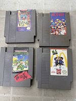 Four NES game cartridges laid out showing label art for Circus Caper, Dr. Mario, Teenage Mutant Ninja Turtles II: The Arcade Game, and M.C. Kids