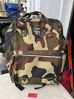 Front view showing camouflage pattern, front zip pocket, top handles and brand patch