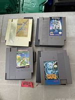 Top view of four NES game cartridges including gold Zelda II and three grey cartridges