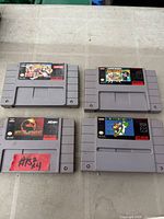 Front view of four grey SNES cartridges: top row Street Fighter II Turbo and Super Punch-Out!!, bottom row Mortal Kombat and Super Mario World