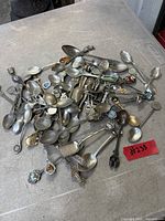 Pile of assorted vintage souvenir teaspoons with varied decorative elements