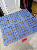 Six blue Whitman coin folders laid out showing filled and empty slots