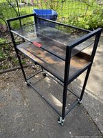 Full view showing two shelves, metal frame, casters, mesh upper shelf, wood lower shelf