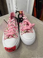 Top view of pair of floral kids sneakers showing pattern, laces, size tag, new condition