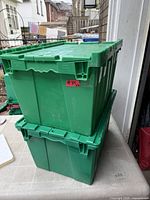 Two stacked green plastic totes with fold-in lids