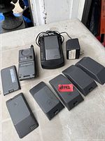 Phone, charger cradle, power adapter, eight batteries laid out