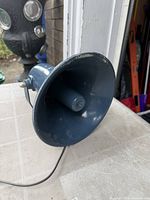 Side view of blue-grey metal PA horn with mounting bracket and attached cable