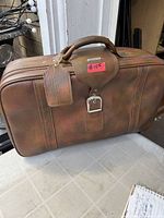 Front view of brown Samsonite suitcase with handle and buckle strap