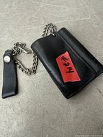 Closed black leather wallet with attached chain and belt strap