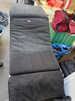 Full view of black padded camping mat showing quilted surface and fold sections