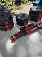 Multiple stacks of octagonal weight plates with red accents alongside two dumbbell bars