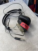 Full view of vintage over-ear headphones showing ear cups, headband, and 1/4-inch plug