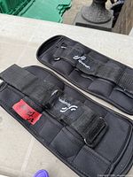 Two black Sportneer adjustable ankle weights showing straps, D-rings, and logos