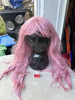Front view of pastel pink long wavy wig on mannequin head
