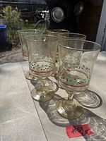 Five 1984 Arby's holly pattern glass goblets displayed outdoors